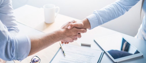 Personen schütteln sich die Hände über einem Meetingstisch