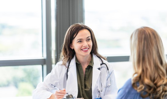 Ärztin notiert sich etwas auf dem Klemmbrett während einem Patientengespräch